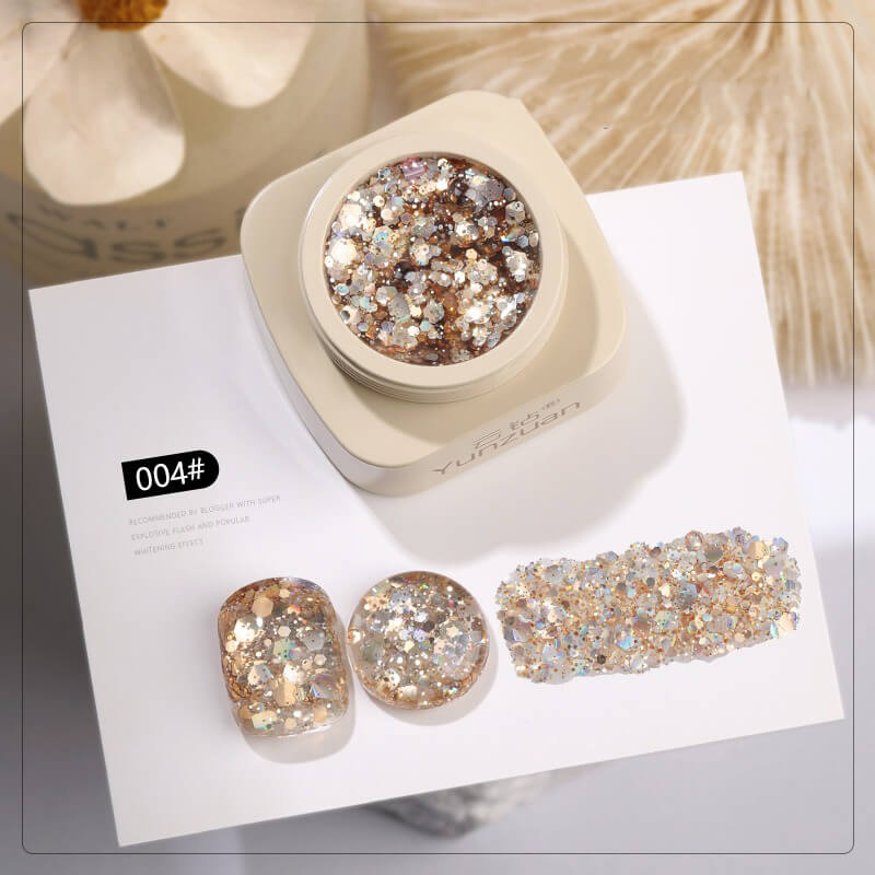 Glittery nail art kit with a container and samples on a white surface.
