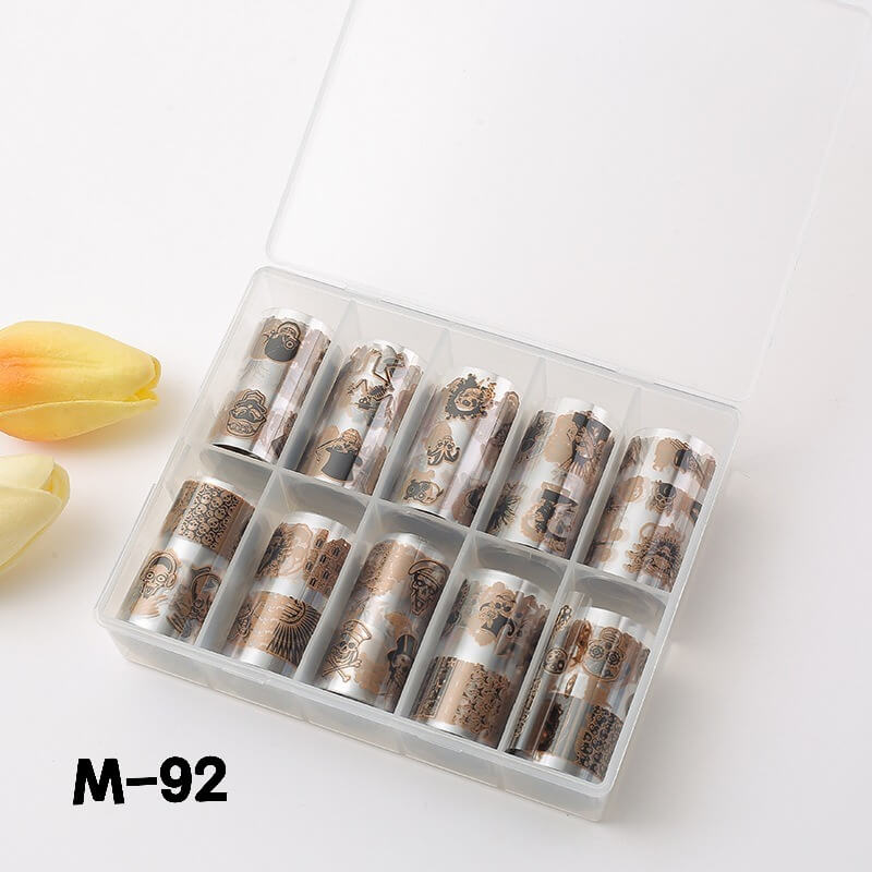 Set of nail art foil rolls in a clear plastic case on a white background with a yellow tulip.