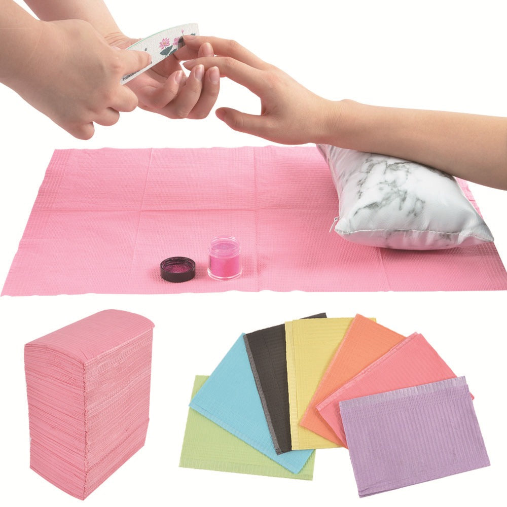 Various disposable nail mats in different colors displayed on a table, with a person using one of the mats for a manicure.