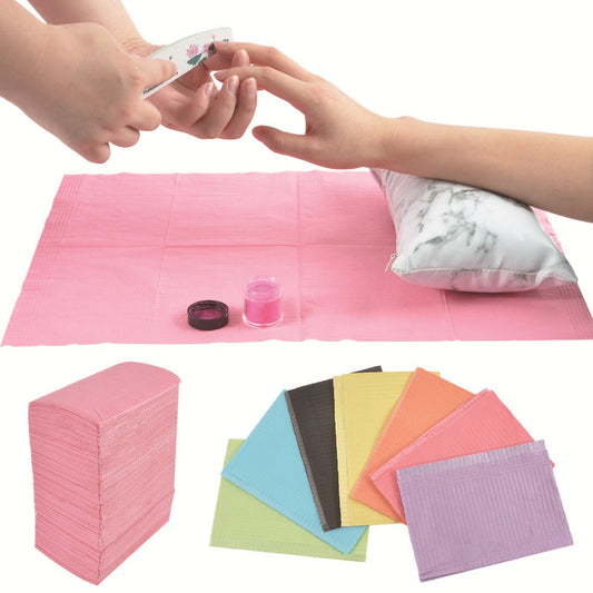 Various disposable nail mats in different colors displayed on a table, with a person using one of the mats for a manicure.