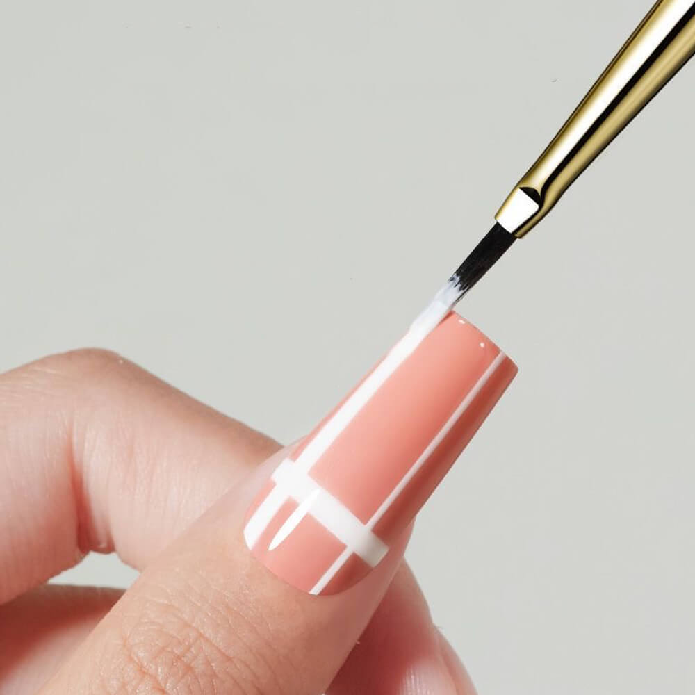 Nail art brush applying white polish to a nail with a plain background