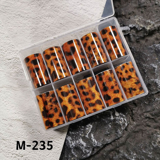 Set of leopard print nail foils in a clear plastic case on a textured surface.