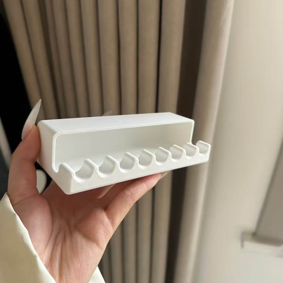 White plastic tray with multiple small compartments held in a hand against a neutral background