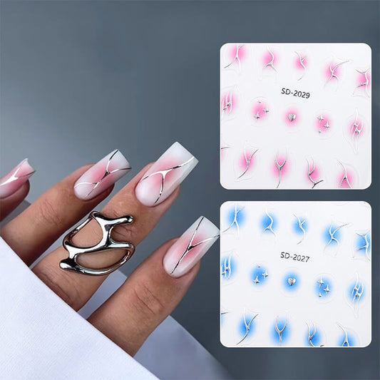 A set of gradient nail decals with a flame design, displayed on a person's hand. The decals show a gradient of pink to blue with decorative elements shaped like flames.