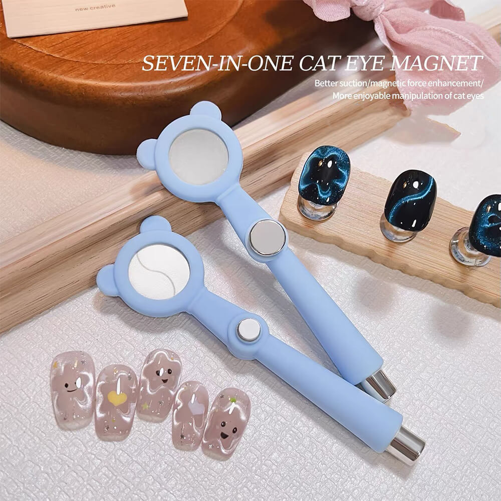 A pair of light blue seven-in-one cat eye magnet nail tools with built-in mirrors, displayed on a textured white surface alongside sample false nails and wooden props.
