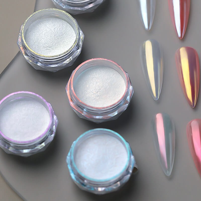 Nail art powders in small jars with nail samples on a gray background