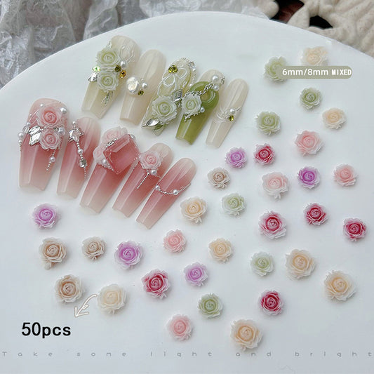 A set of nail studs and decorations with rose-shaped designs, featuring different colors and adorned with rhinestones, displayed on a plate.