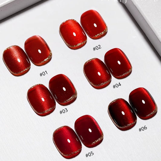Various swatches of red cat eye nail gel polish with different shades and finishes displayed on a surface.