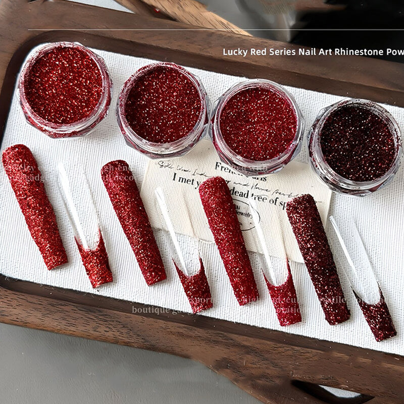 Red glittery nail art rhinestone powders on a wooden tray with a white cloth background.