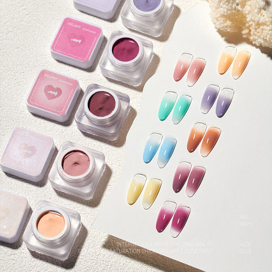 Various shades of semi-solid nail gels displayed in small pots, with a French Ombre effect patten painting gel shown on a sheet alongside them.