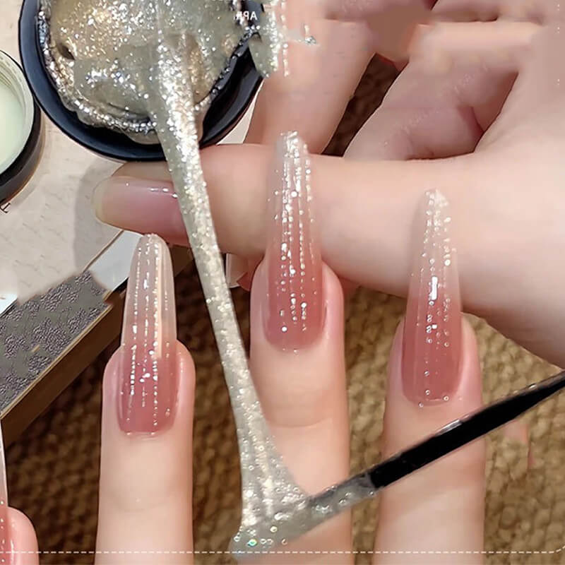 Close-up of hands with glittery spider nail gel polish and a brush.