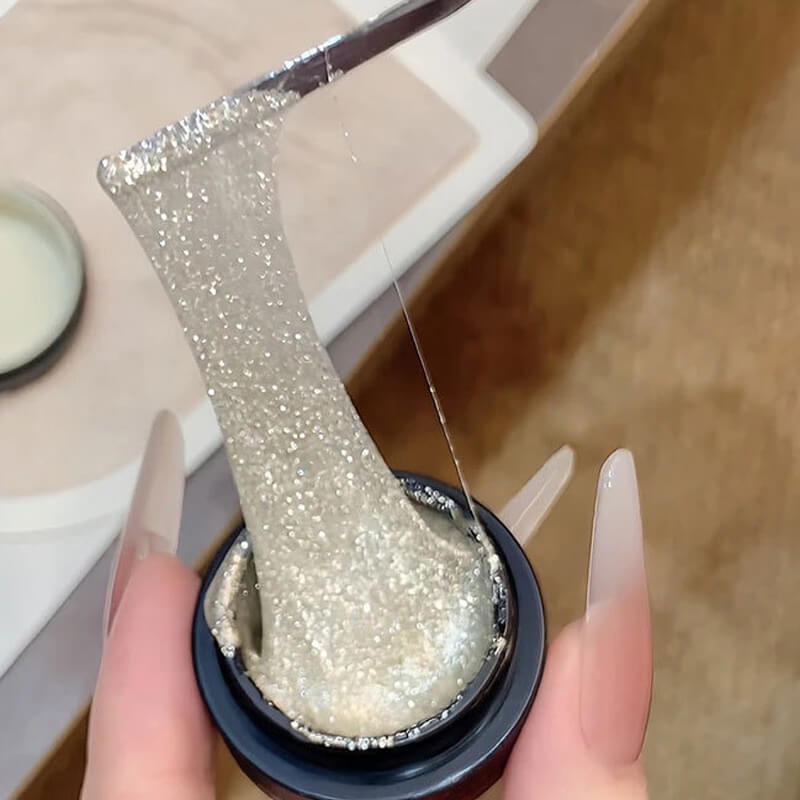 Close-up of a glittery gel nail polish being applied with a brush.