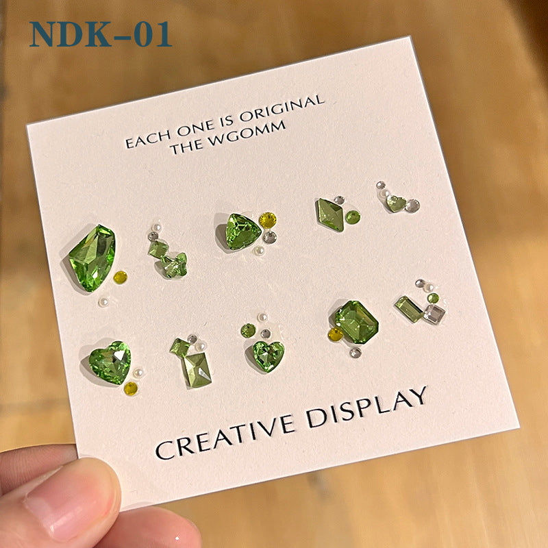 A set of nail art rhinestone gem kits displayed on a card, with various shades of green and other colors.