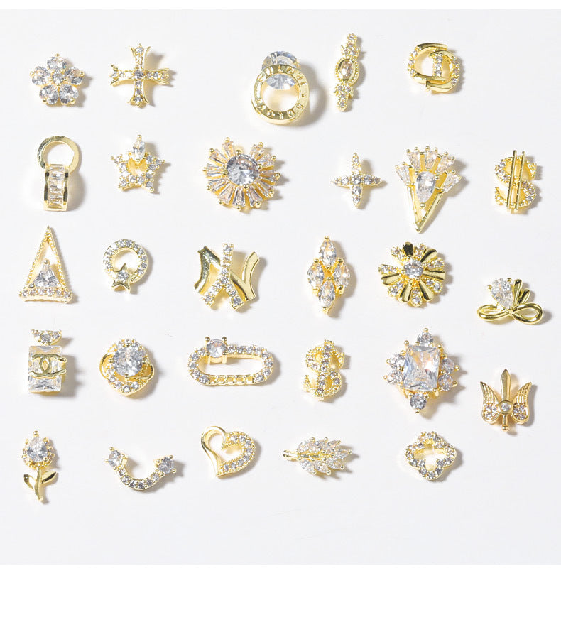 A collection of 28 shiny rhinestone nail decoration ornaments in various shapes including stars, hearts, and bowknots, primarily in gold and silver colors.