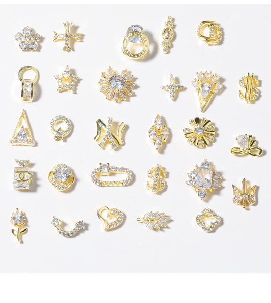 A collection of 28 shiny rhinestone nail decoration ornaments in various shapes including stars, hearts, and bowknots, primarily in gold and silver colors.