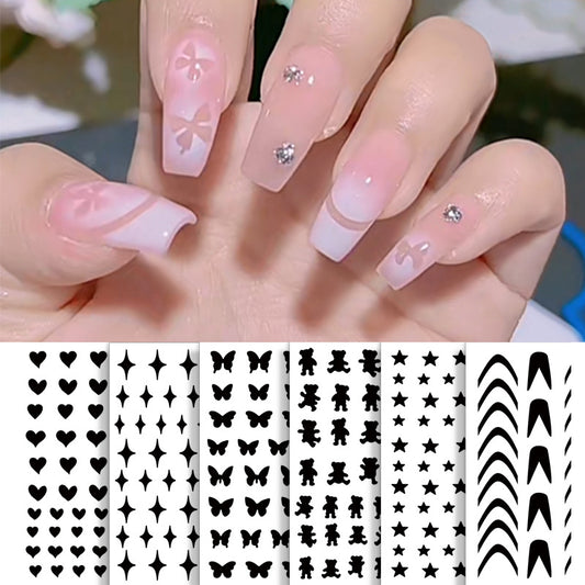 A set of nail stickers with various designs including butterflies, hearts, and stars, displayed on a person's fingernails.