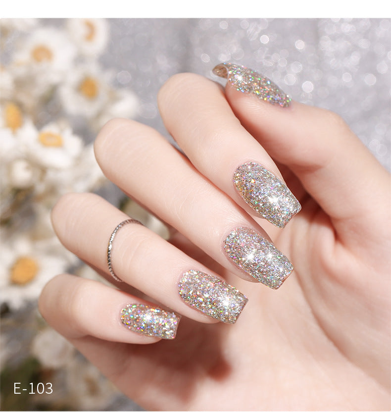 A photo showing a pair of hands with fingernails painted in glitter nail polish, with a visible glittery finish. The hands are adorned with a sparkling, multicolored design.