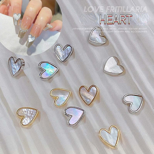 A collection of 3D fritillary peach heart alloy jewelry diamond rhinestones for nail DIY, displayed on a white surface. The rhinestones are in various colors including clear, peach, and heart-shaped with a shimmering effect.