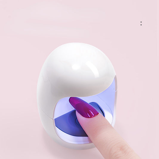 Compact white and blue mini LED nail lamp with a finger pressed against it, indicating use for nail drying.