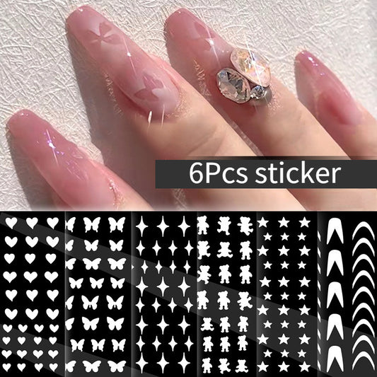 A set of 6 nail stickers with various designs such as stars, butterflies, and floral patterns applied on a person's nails.